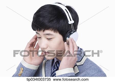 Stock Photography - a male student listening on a headphone. Fotosearch