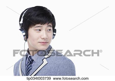 Stock Photo - a male student looking behind while wearing a headphone. Fotosearch