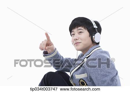Stock Photo - a male student pointing while wearing a headphone. Fotosearch