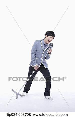 a male student singing while grabbing a microphone stand View Large Photo Image Stock Photo - a male student singing while grabbing a microphone stand . Fotosearch
