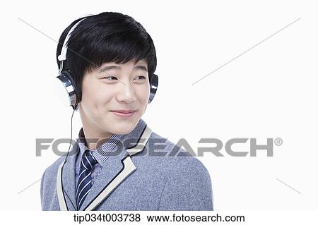 Stock Photo - a male student smiling while wearing a headphone. Fotosearch