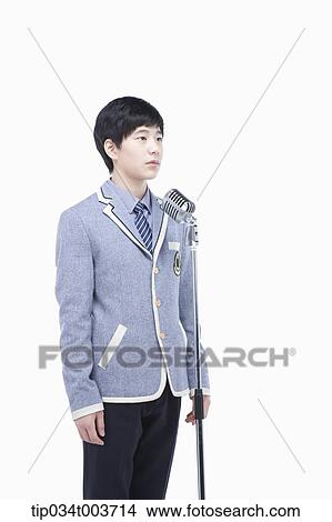 a male student standing behind a microphone stand View Large Photo Image Picture - a male student standing behind a microphone stand . Fotosearch