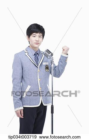 Stock Photo - a male student standing behind a microphone stand with raising fist gesture. Fotosearch