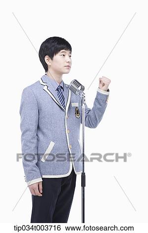 Stock Photograph - a male student standing behind a microphone stand with raising fist gesture. Fotosearch
