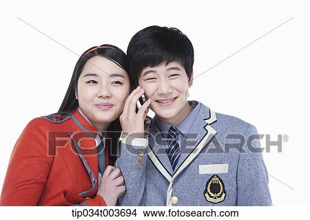 a male student talking on a mobile phone while female student tries to overhear View Large Photo Image Picture - a male student talking on a mobile phone while female student tries to overhear. Fotosearch