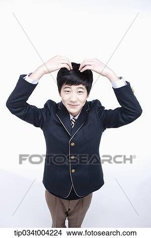 Picture - a male student wearing school uniform making heart symbol with arms . Fotosearch
