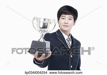 Picture - a male student wearing school uniform holding a trophy cup. Fotosearch