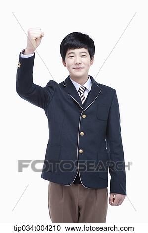 Stock Image - a male student wearing school uniform standing with a fist up. Fotosearch