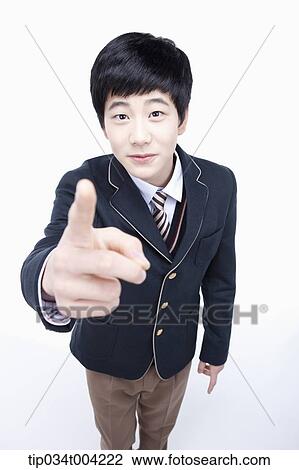 Stock Image - a male student wearing school uniform pointing at camera. Fotosearch