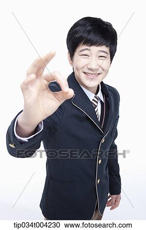 Stock Image - a male student wearing school uniform showing ok sign . Fotosearch