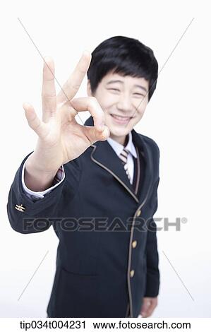 Stock Image - a male student wearing school uniform showing ok sign . Fotosearch