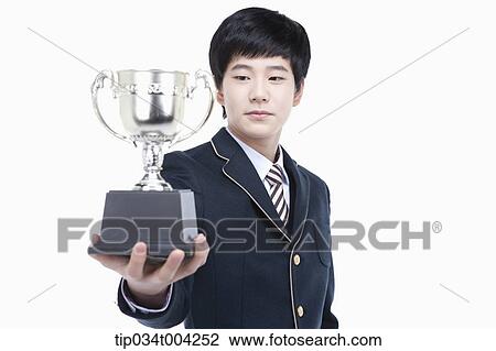 Stock Image - a male student wearing school uniform holding a trophy cup. Fotosearch
