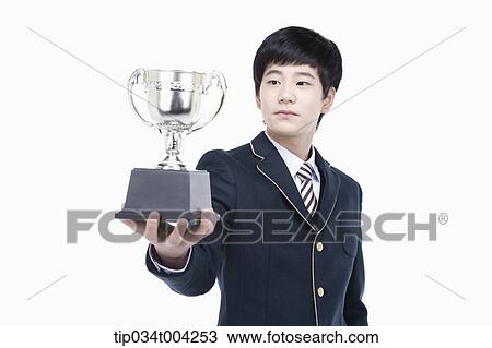 Stock Image - a male student wearing school uniform holding a trophy cup. Fotosearch