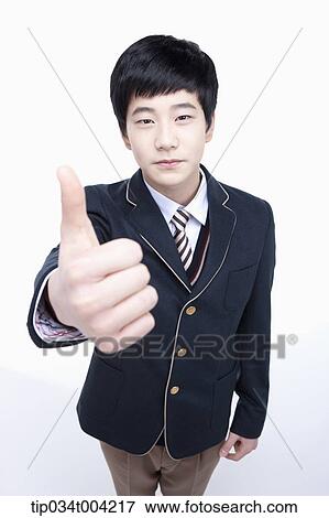 Stock Photo - a male student wearing school uniform posing thumbs up. Fotosearch