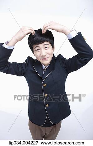 Stock Photo - a male student wearing school uniform making heart symbol with arms . Fotosearch