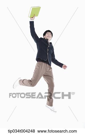 a male student wearing school uniform jumping while holding a book View Large Photo Image Stock Photo - a male student wearing school uniform jumping while holding a book. Fotosearch