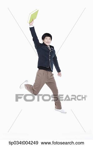 Stock Photo - a male student wearing school uniform jumping while holding a book. Fotosearch