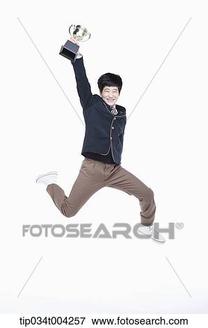 Stock Photo - a male student wearing school uniform jumping with a trophy cup. Fotosearch