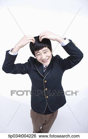 Stock Photograph - a male student wearing school uniform making heart symbol with arms . Fotosearch