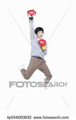 Stock Image - a male student with boxing gloves jumping while raising his arm up. Fotosearch