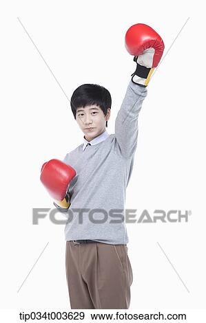 Stock Photo - a male student with boxing gloves raising his arm up. Fotosearch