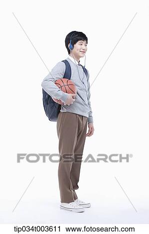 Stock Image - a male student with headphones holding a basketball in his arm. Fotosearch