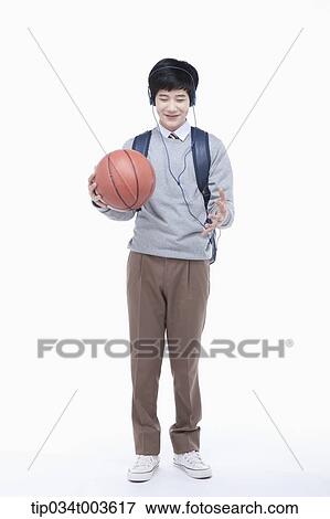 Stock Photo - a male student with headphones playing with a basketball . Fotosearch