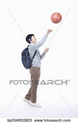 Stock Photography - a male student with headphones shooting a basketball in the air. Fotosearch