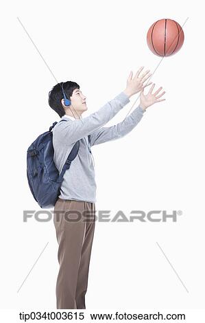 Stock Photography - a male student with headphones throwing a basketball in the air. Fotosearch