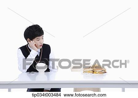 a male student with school uniform staring at burgers while sitting in front of rice bowl View Large Photo Image Picture - a male student with school uniform staring at burgers while sitting in front of rice bowl. Fotosearch