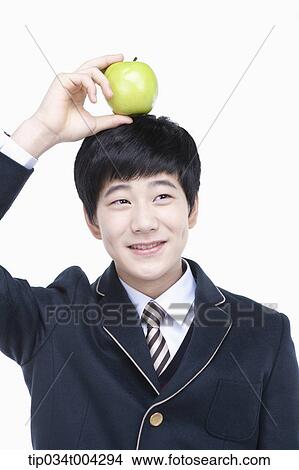 a male student with school uniform balancing an apple in his head View Large Photo Image Picture - a male student with school uniform balancing an apple in his head. Fotosearch