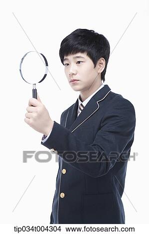 a male student with school uniform looking through a magnifying glass View Large Photo Image Picture - a male student with school uniform looking through a magnifying glass. Fotosearch