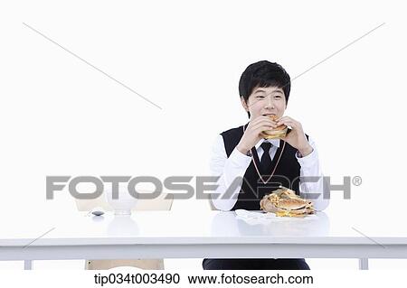 Stock Image - a male student with school uniform eating burgers. Fotosearch