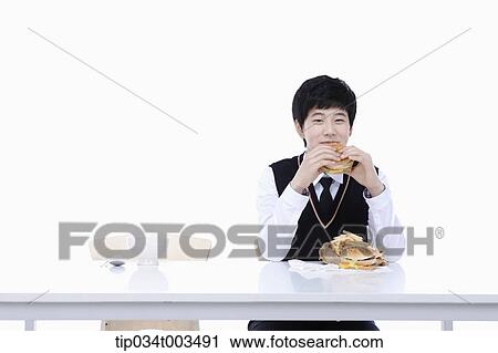 Stock Image - a male student with school uniform eating burgers. Fotosearch