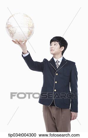 Stock Image - a male student with school uniform holding a globe with one hand . Fotosearch