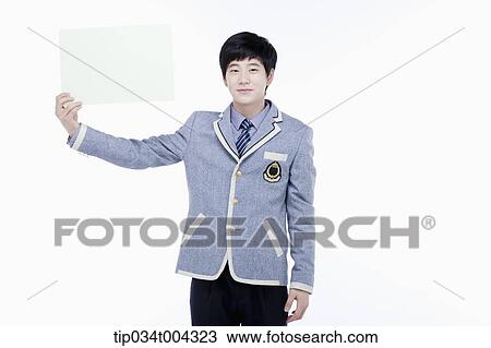 Stock Image - a male student with school uniform holding an empty white paper . Fotosearch