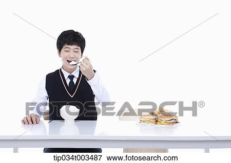 Stock Photo - a male student with school uniform eating rice . Fotosearch