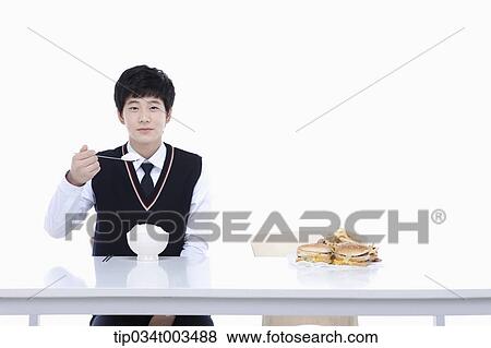Stock Photo - a male student with school uniform eating rice . Fotosearch