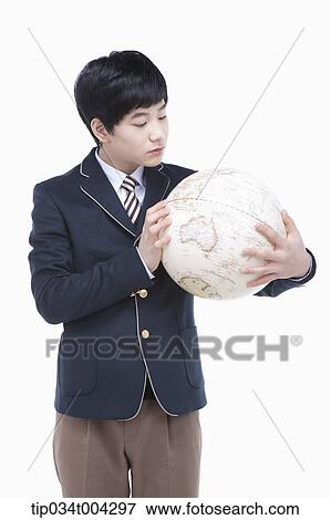 Stock Photo - a male student with school uniform looking at a globe. Fotosearch
