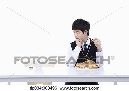 Stock Photograph - a male student with school uniform staring at burgers while having French fries . Fotosearch