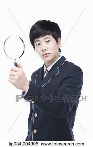 Stock Photograph - a male student with school uniform holding a magnifying glass. Fotosearch