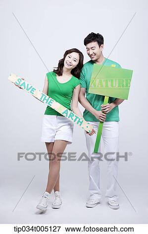 Stock Photo - a man and a woman holding signboard and picket with environmentally friendly phrases. Fotosearch