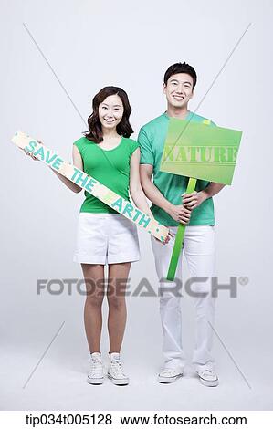 Stock Photo - a man and a woman holding signboard and picket with environmentally friendly phrases. Fotosearch