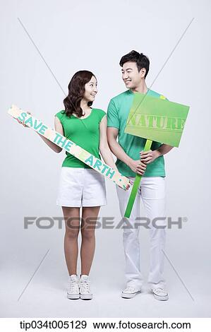 Stock Photo - a man and a woman holding signboard and picket with environmentally friendly phrases. Fotosearch