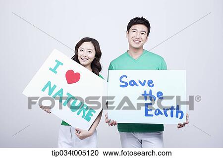 Stock Image - a man and a woman holding signboards with environmentally friendly phrases. Fotosearch