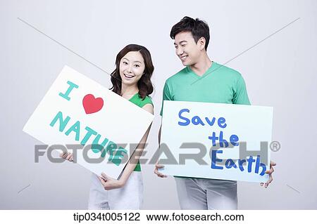Stock Image - a man and a woman holding signboards with environmentally friendly phrases. Fotosearch
