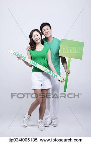 Stock Photography - a man and a woman holding signboards saying environmentally friendly phrases. Fotosearch