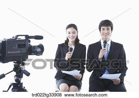 Stock Photo - a man and a woman in black suit sitting with microphones next to studio camera. Fotosearch
