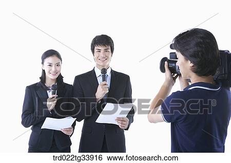 a man and a woman in black suit announcing with microphones in front of studio camera View Large Photo Image Stock Photograph - a man and a woman in black suit announcing with microphones in front of studio camera. Fotosearch