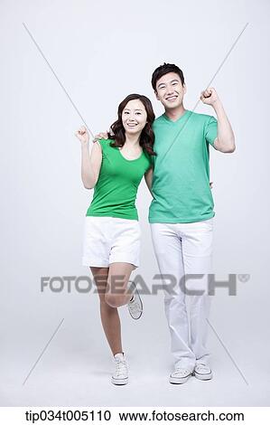 Stock Image - a man and a woman in green t-shirt posing cheering gesture. Fotosearch